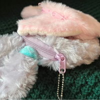 Close-up of a fluffy white dog with a pink and green toy, wearing a pink glove.