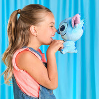 Young girl holding a blue plush toy against a blue curtain background