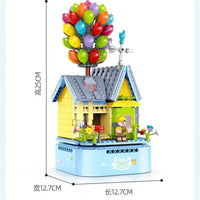 Product packaging with toy house, balloons, and packaging design on a blue background