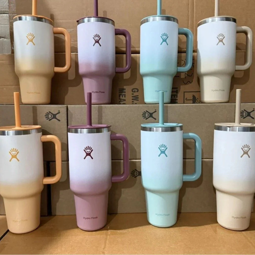 Set of colorful travel mugs with straws on a wooden surface.
