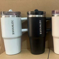Three Stanley tumblers in different colors on a surface.