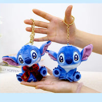 Two blue plush toys resembling a character with pink ears held by hands against a light background.