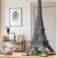 Model of the Eiffel Tower on a table in a room with a man sitting in the background.