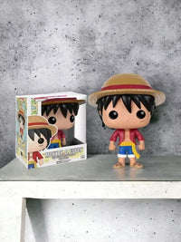 Funko Pop! figurine of Monkey D. Luffy next to its packaging on a gray surface.