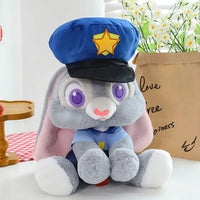 Plush toy rabbit in a police uniform with a blue cap and yellow star, sitting on a white surface with flowers in the background.