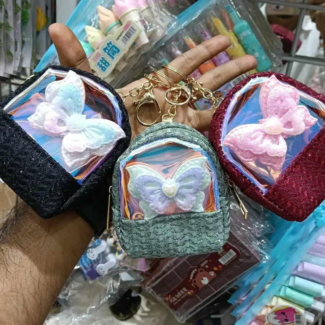 Hand holding small decorative bags with butterfly designs in a store setting
