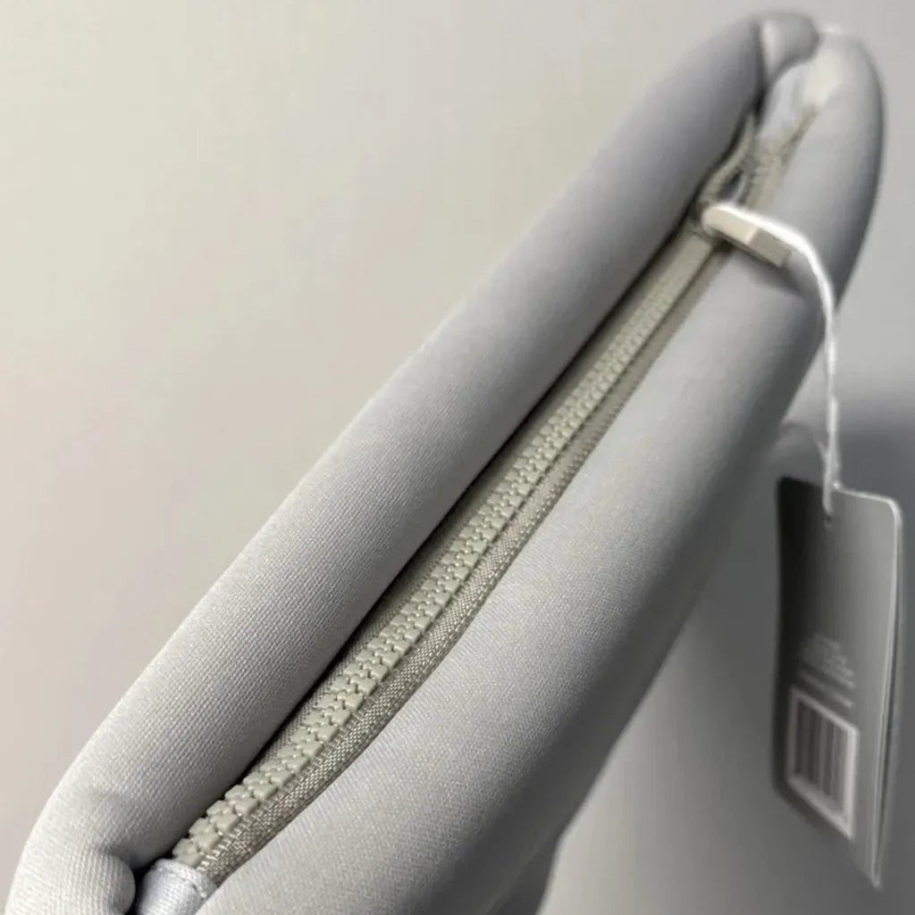 Gray cushion with a zipper and a tag on a light gray background