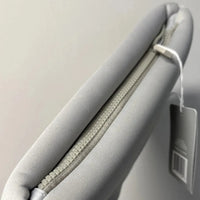 Gray cushion with a zipper and a tag on a light gray background