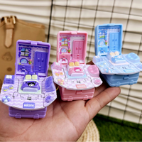 Three small toy houses on a hand with a checkered background